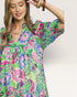 Woman wearing a colorful floral dress against a plain background