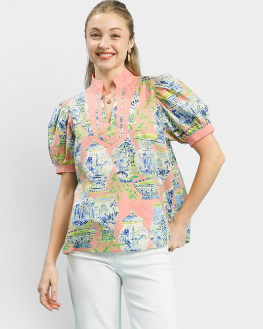 Woman wearing a colorful patterned blouse with a plain background