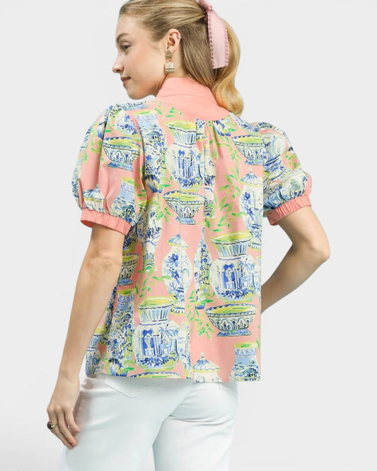 Woman wearing a colorful patterned blouse with a white background