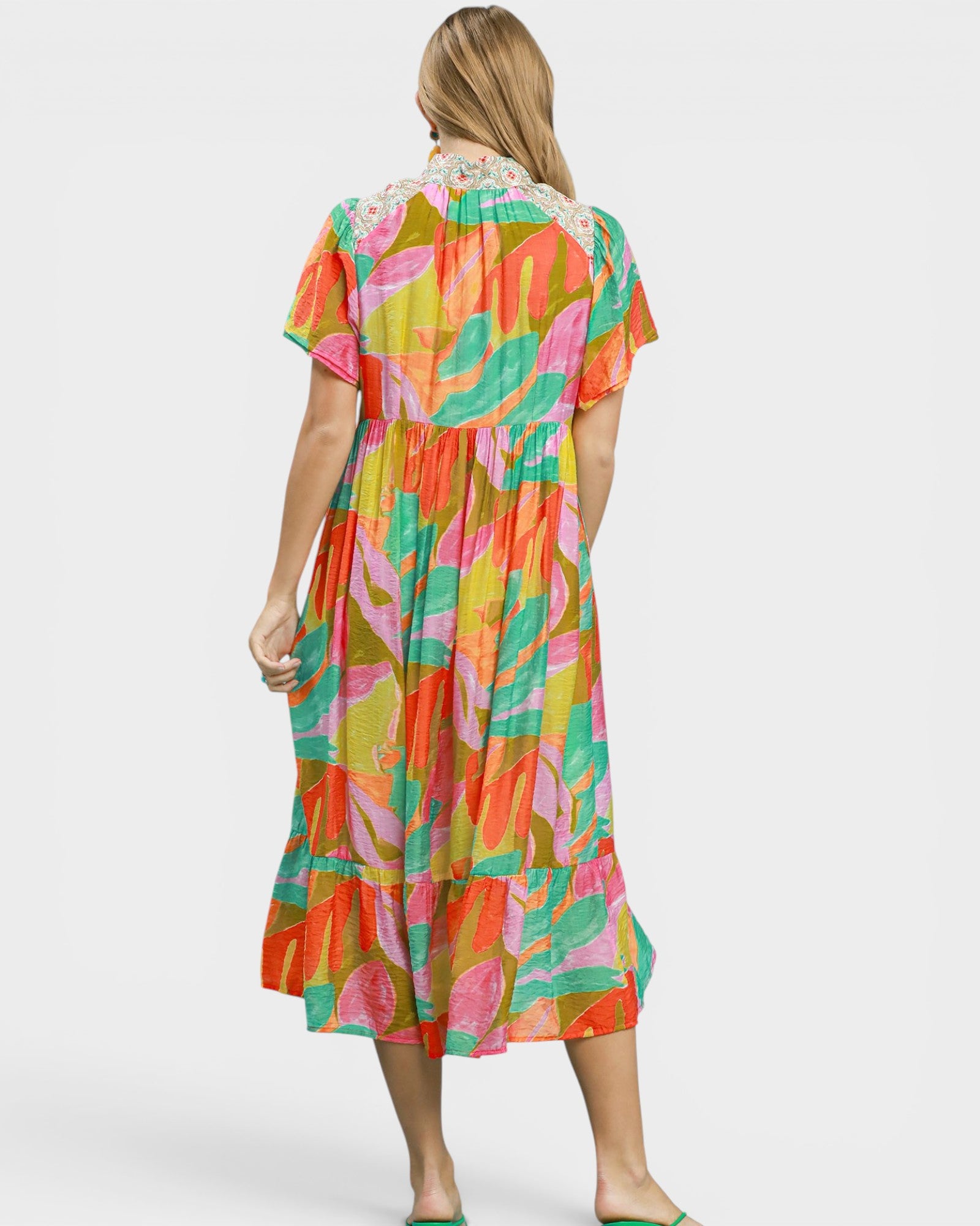 Woman wearing a colorful dress with a leaf pattern on a white background