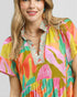 Woman wearing a colorful floral dress with a plain background