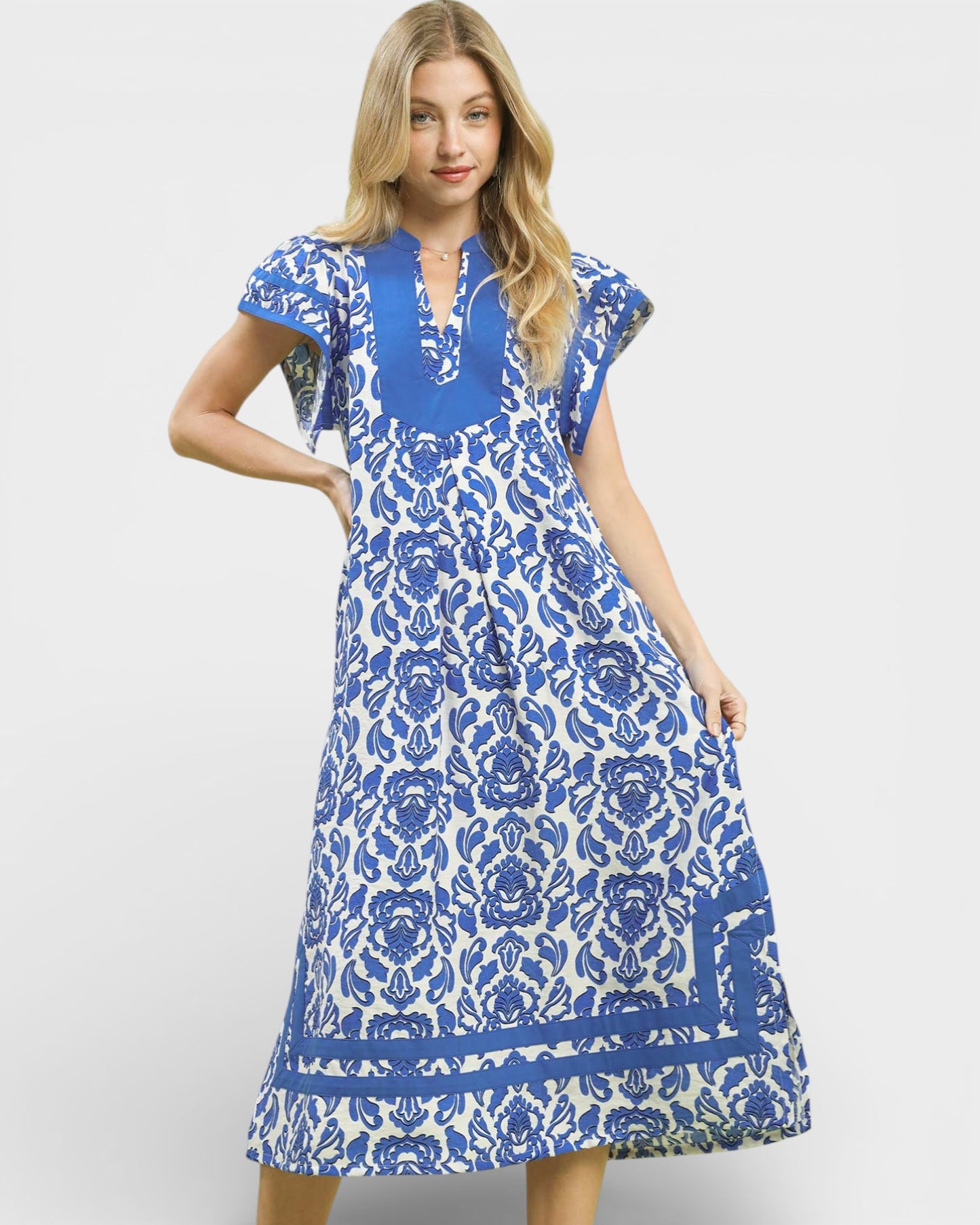 Woman wearing a blue and white floral dress on a light gray background