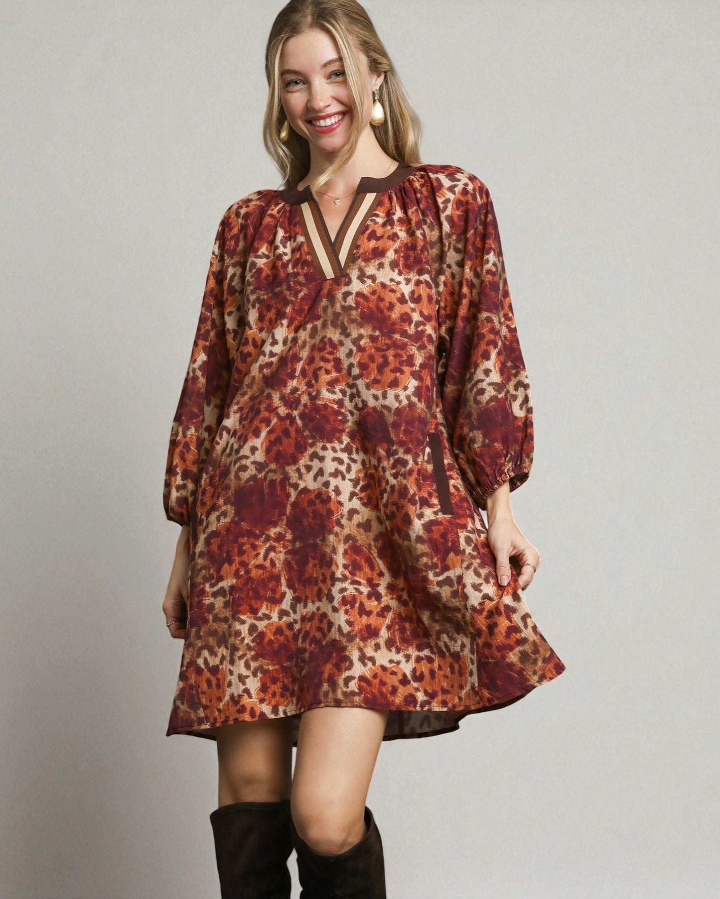 Woman wearing a patterned dress with long sleeves on a plain background