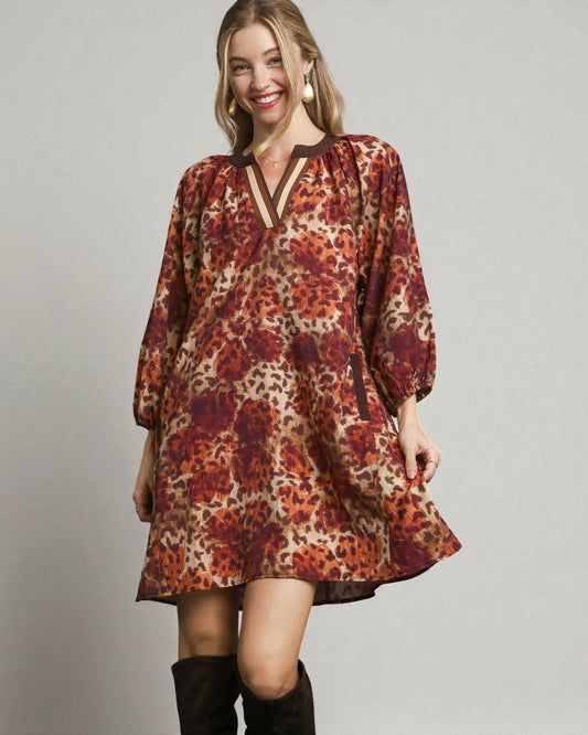 Woman wearing a patterned dress with long sleeves on a plain background