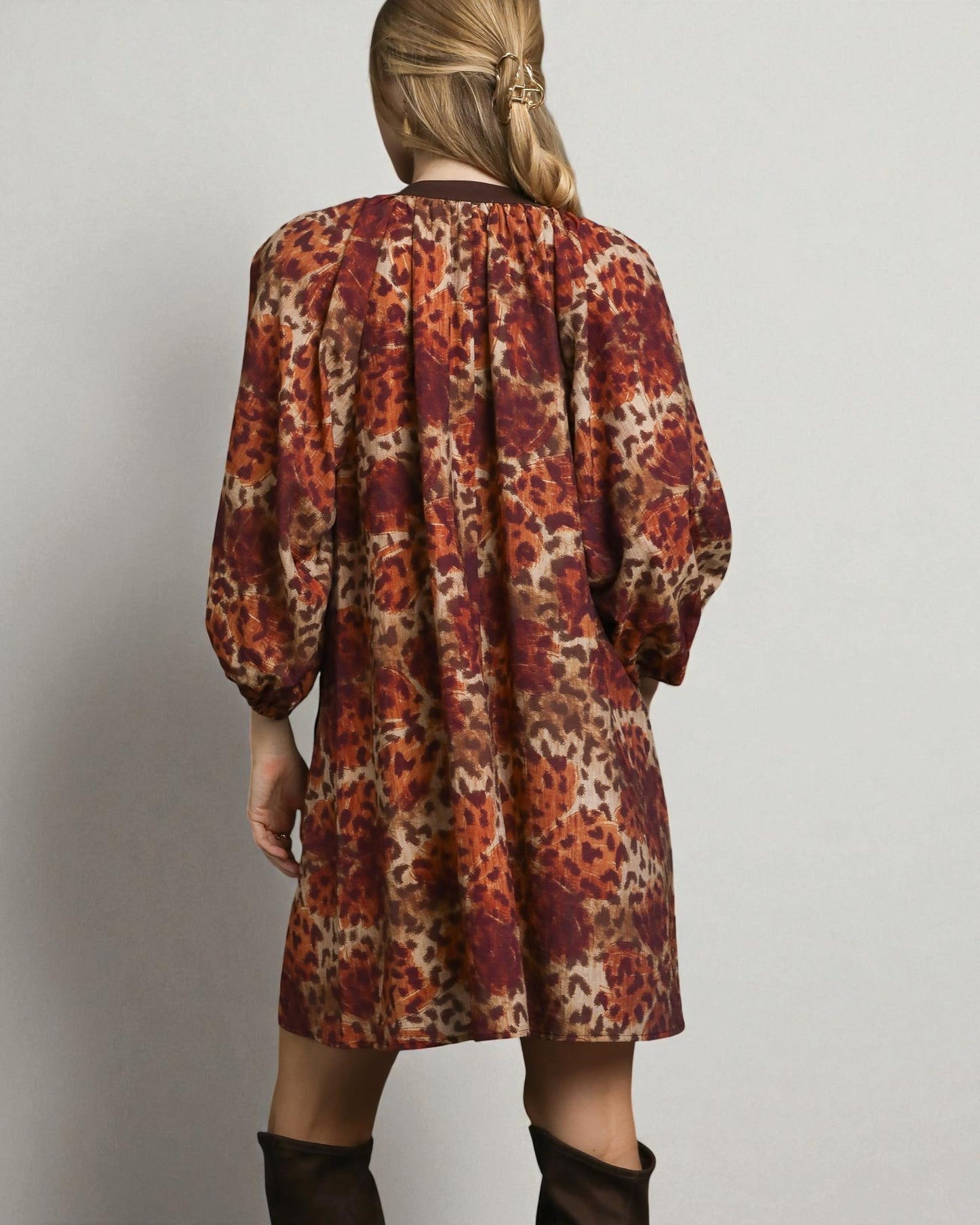 Person wearing a patterned dress with long sleeves on a plain background