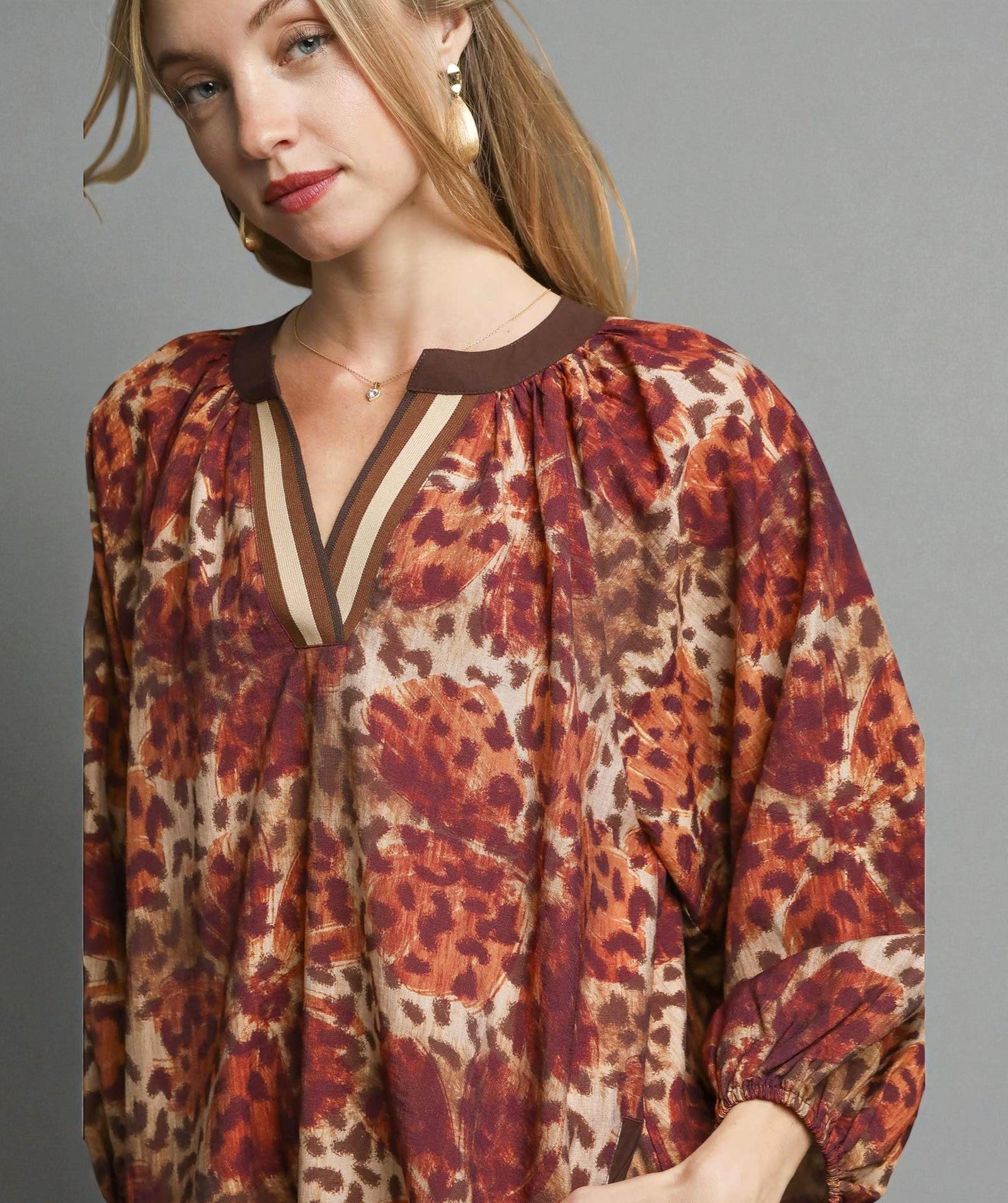 Woman wearing a patterned blouse with a neutral background