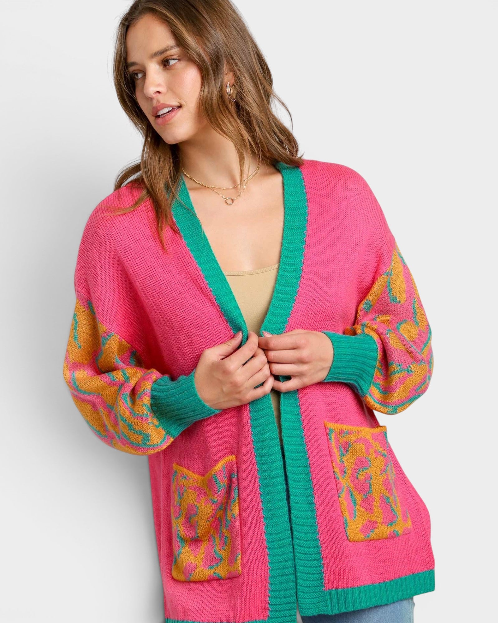 Woman wearing a colorful pink and green cardigan with patterned sleeves on a white background