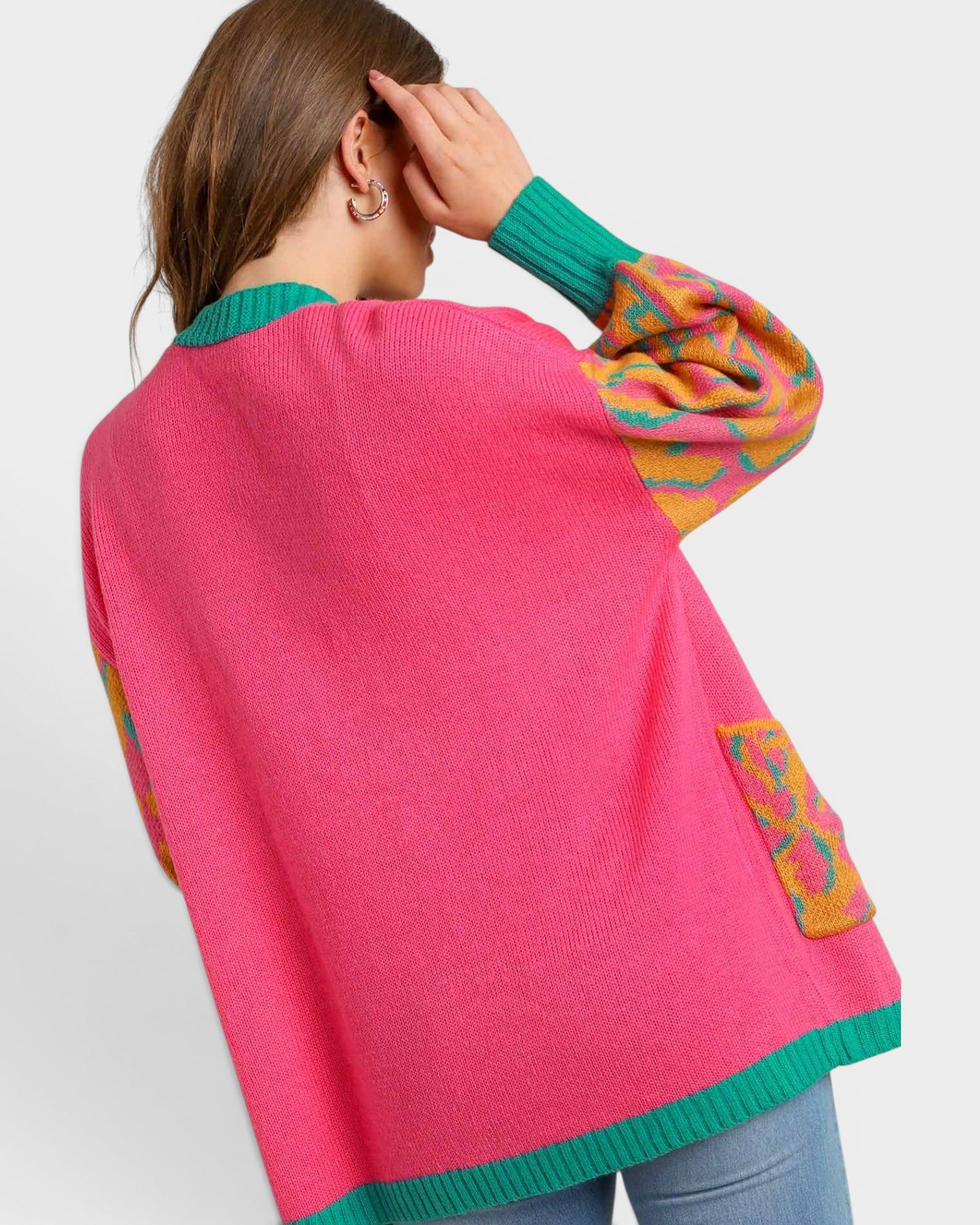 Person wearing a colorful sweater with pink back and multicolor sleeves on a light gray background