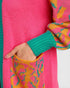 Close-up of a colorful sweater with pink, green, and orange patterns.