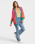 Woman wearing a colorful cardigan, beige top, blue jeans, and white sneakers on a light gray background