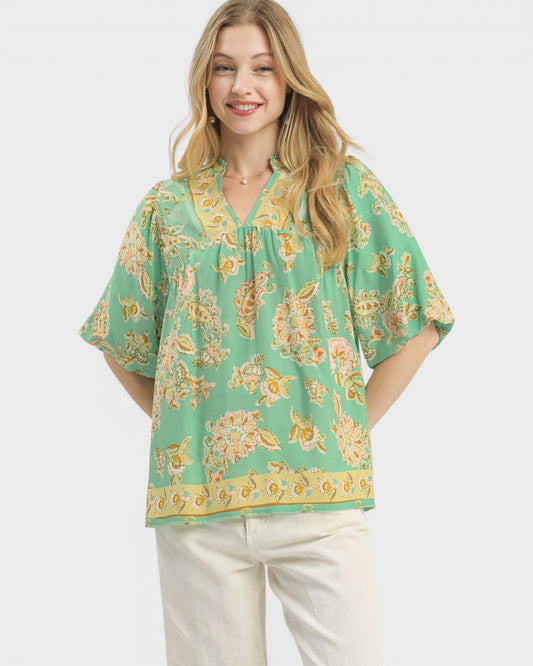 Woman wearing a green floral blouse with a plain background