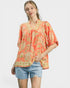 Woman wearing a floral blouse and denim shorts on a white background