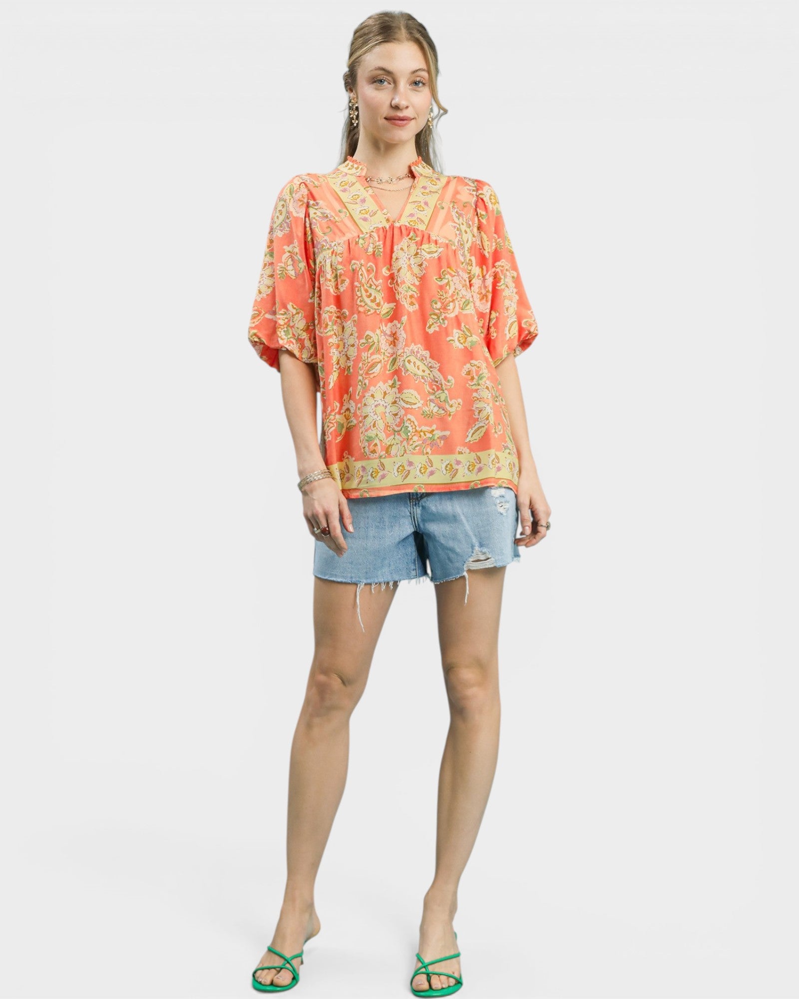 Woman wearing a floral blouse and denim shorts on a white background