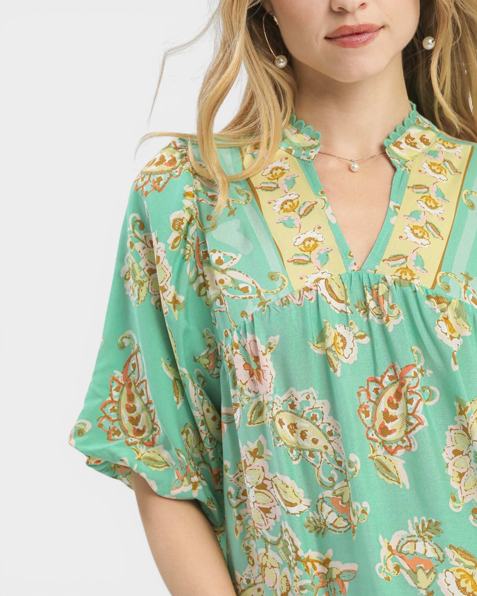 Woman wearing a green floral patterned dress against a white background