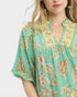 Woman wearing a green floral patterned dress against a white background
