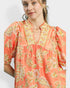Woman wearing a coral floral dress with a plain background