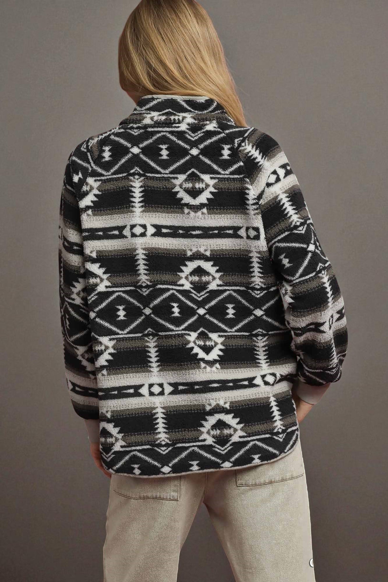 Person wearing a black and white patterned jacket against a gray background