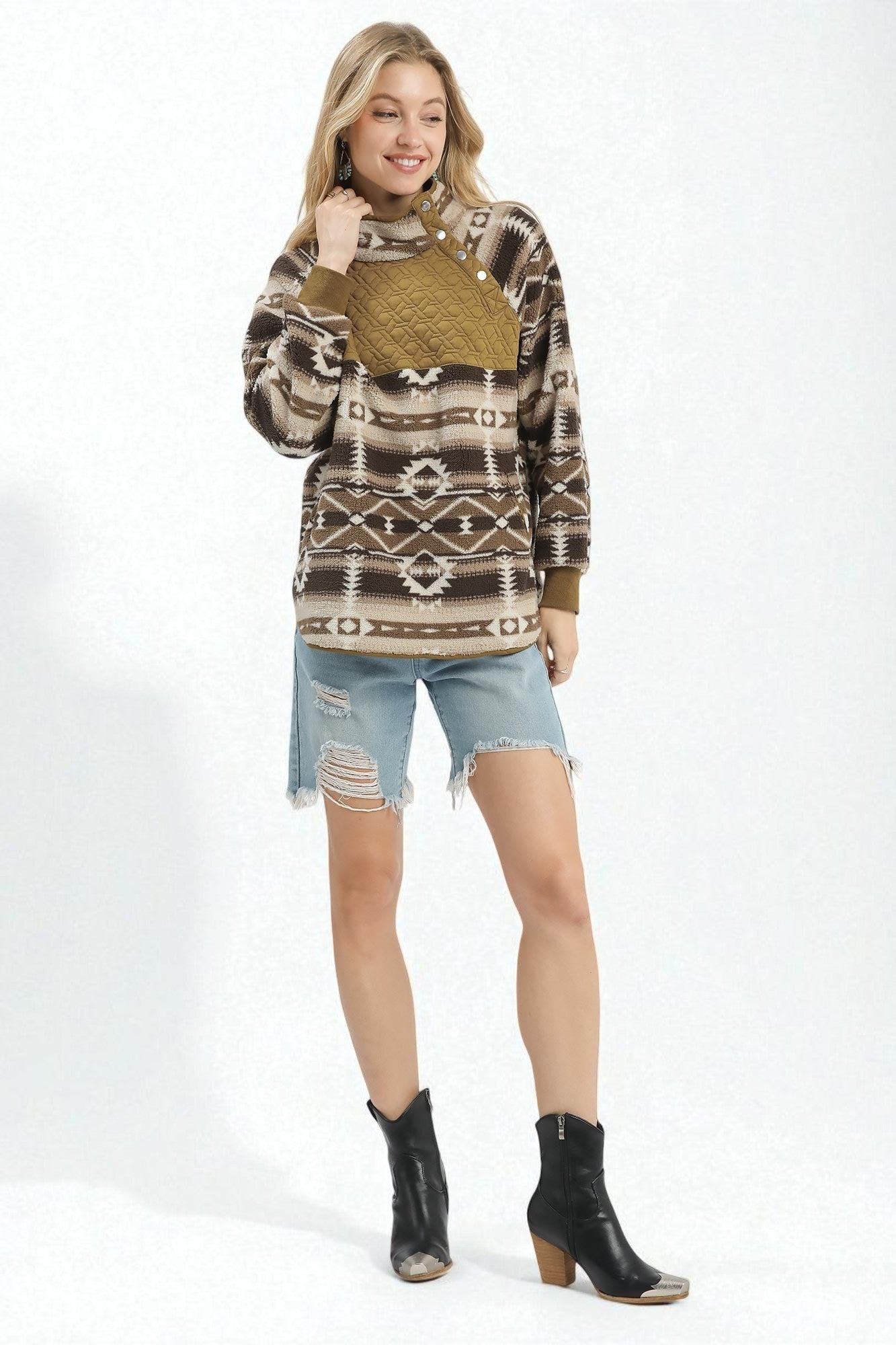 Woman wearing a patterned sweater, denim shorts, and black boots on a white background