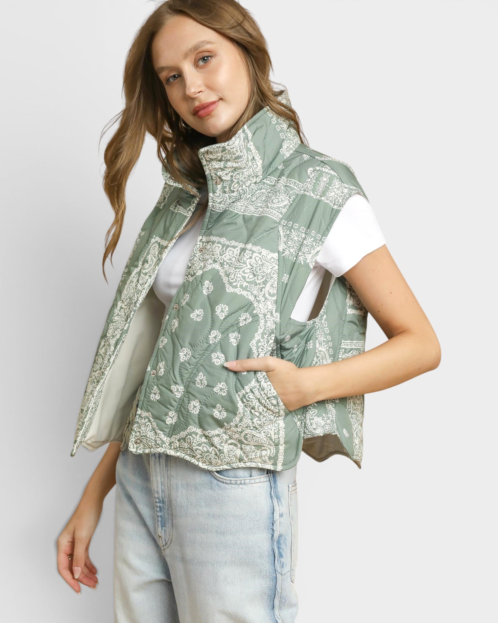 Woman wearing a green patterned vest over a white shirt on a light gray background