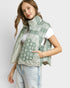 Woman wearing a green patterned vest over a white shirt on a light gray background