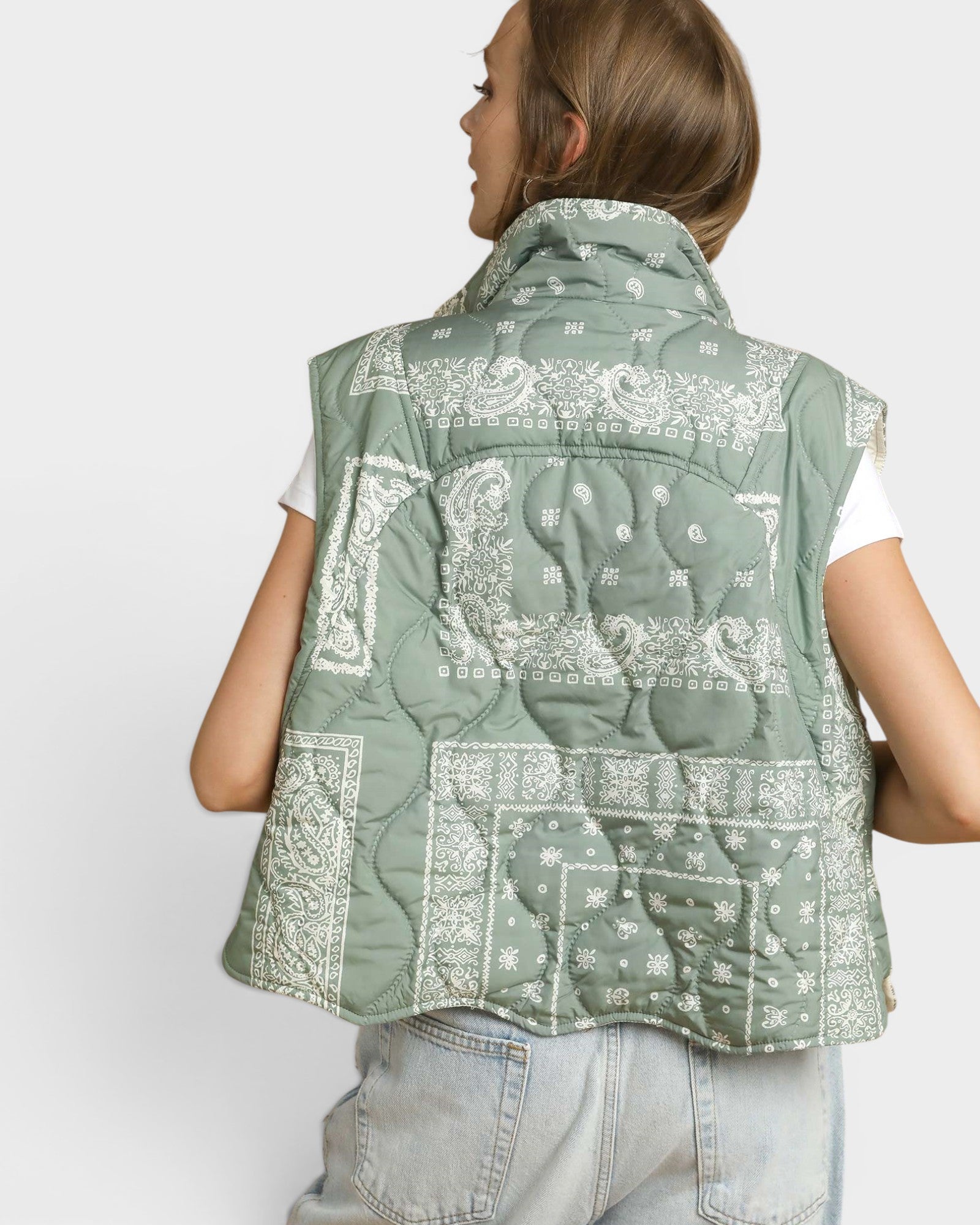 Person wearing a green patterned vest on a white background