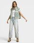 Woman wearing a green patterned vest, white shirt, light blue jeans, and brown boots on a white background