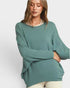 Woman wearing a teal sweater on a white background