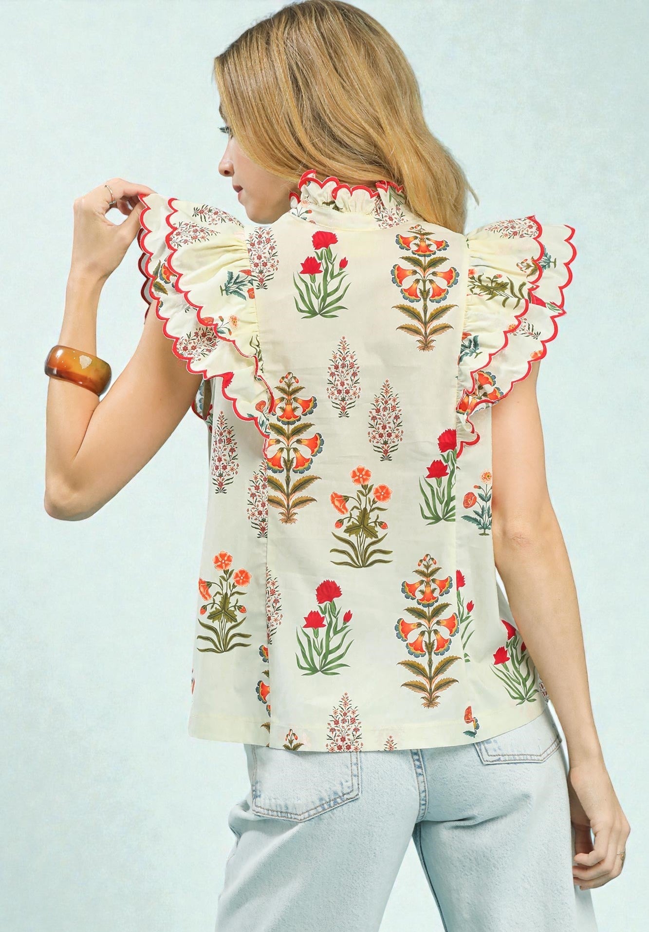 Woman wearing a floral blouse with ruffled sleeves on a light blue background