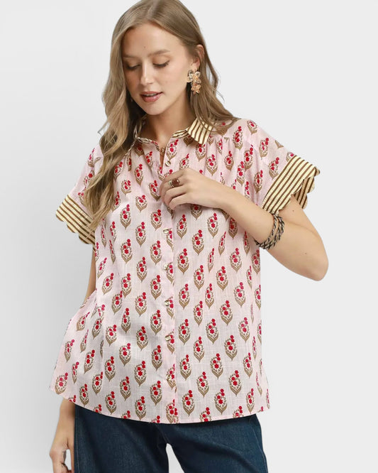 Woman wearing a patterned blouse with gold accents on a white background