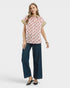 Woman wearing a patterned blouse and blue jeans on a white background