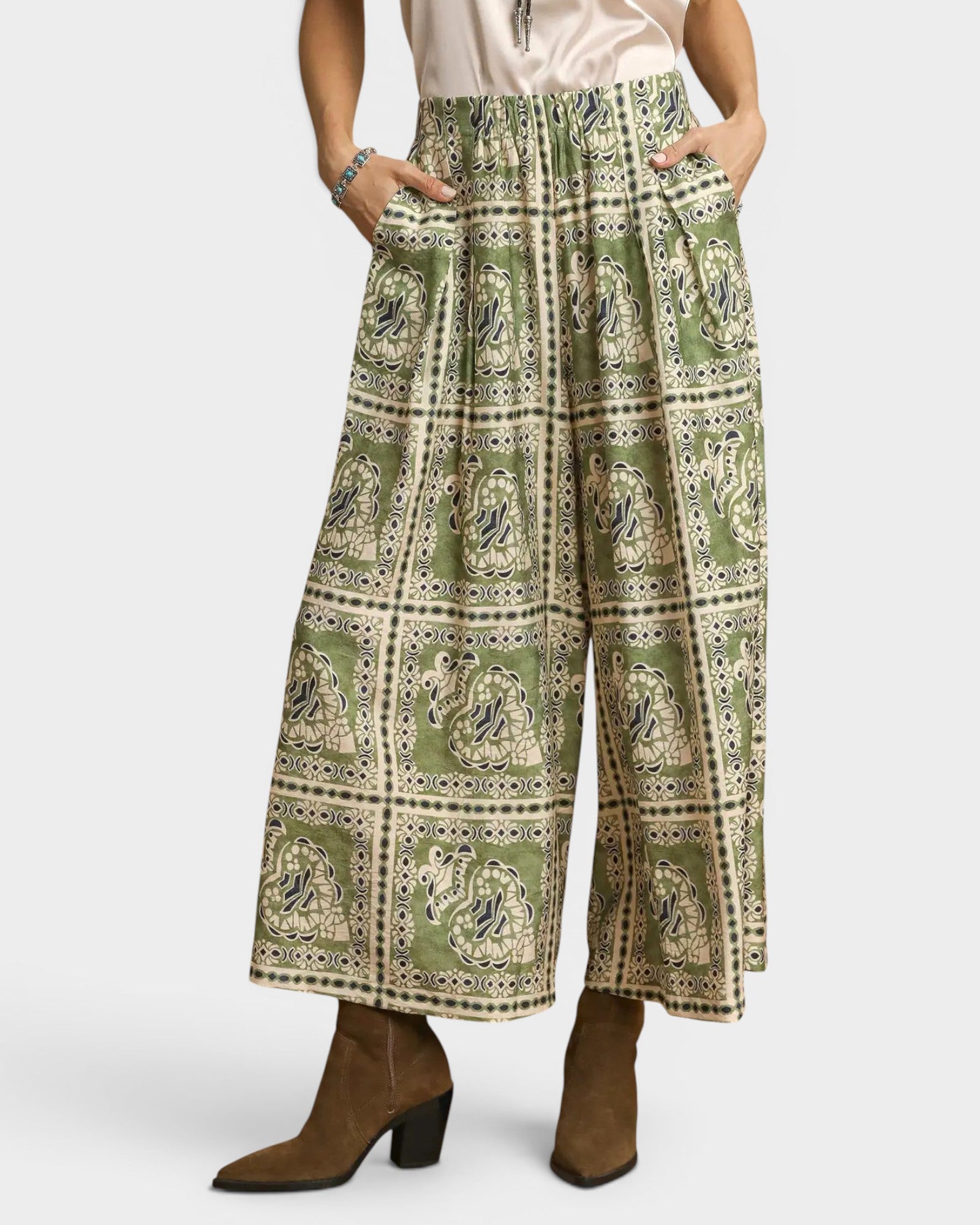Green patterned wide-leg pants worn by a person on a white background