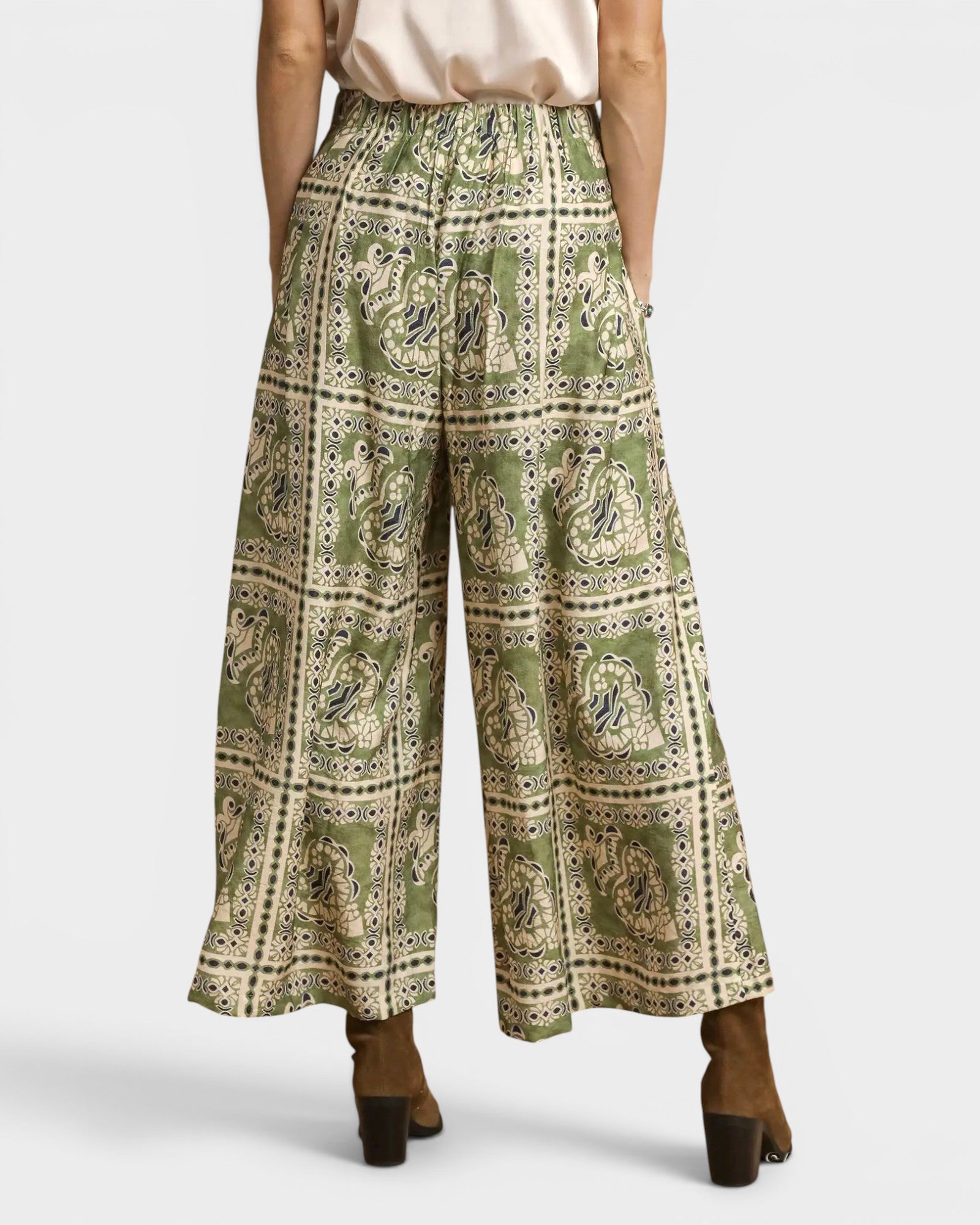 Green patterned wide-leg pants worn by a person on a white background