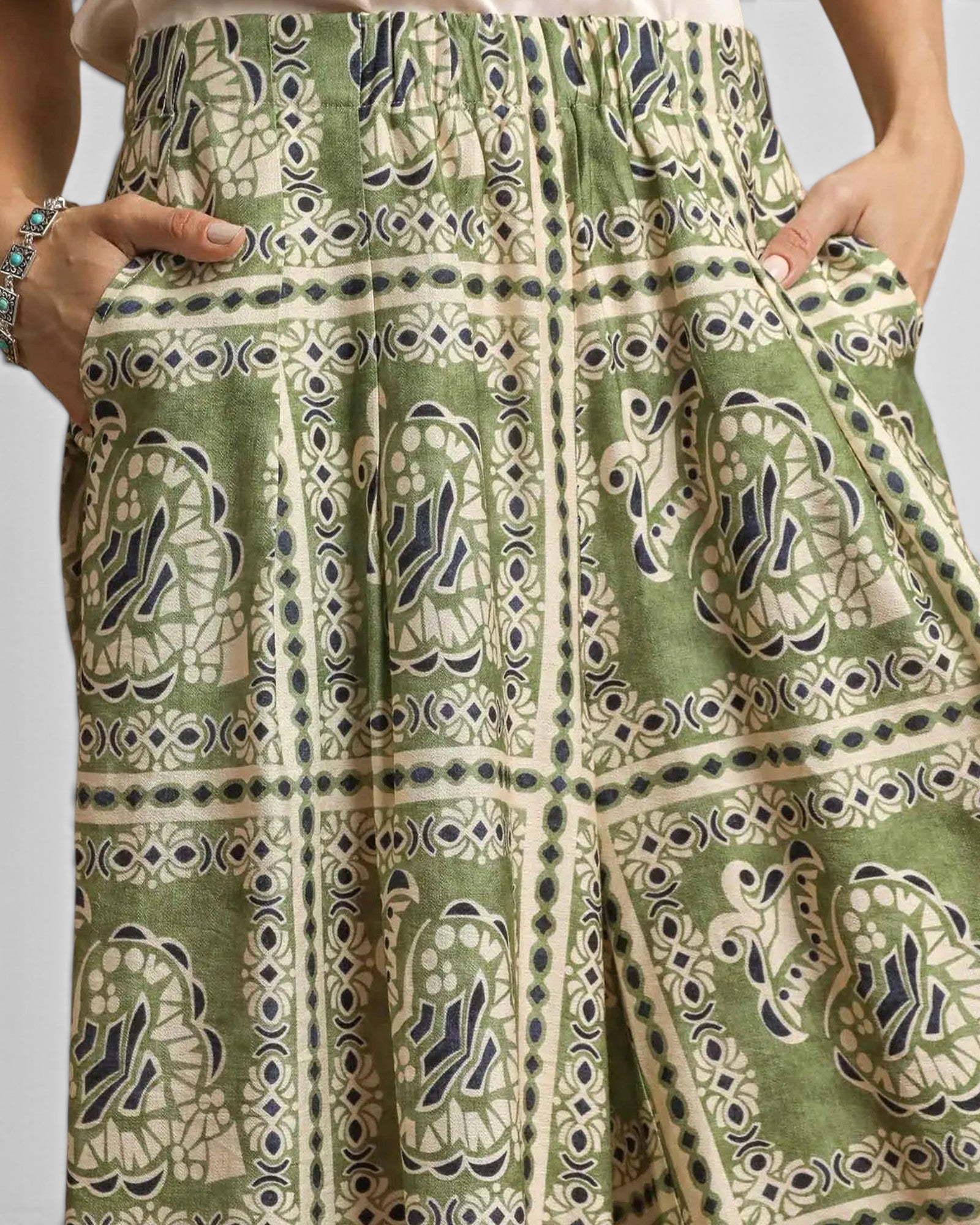 Green patterned skirt with hands in pockets on a neutral background