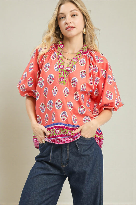 Woman wearing a colorful patterned blouse with a plain background