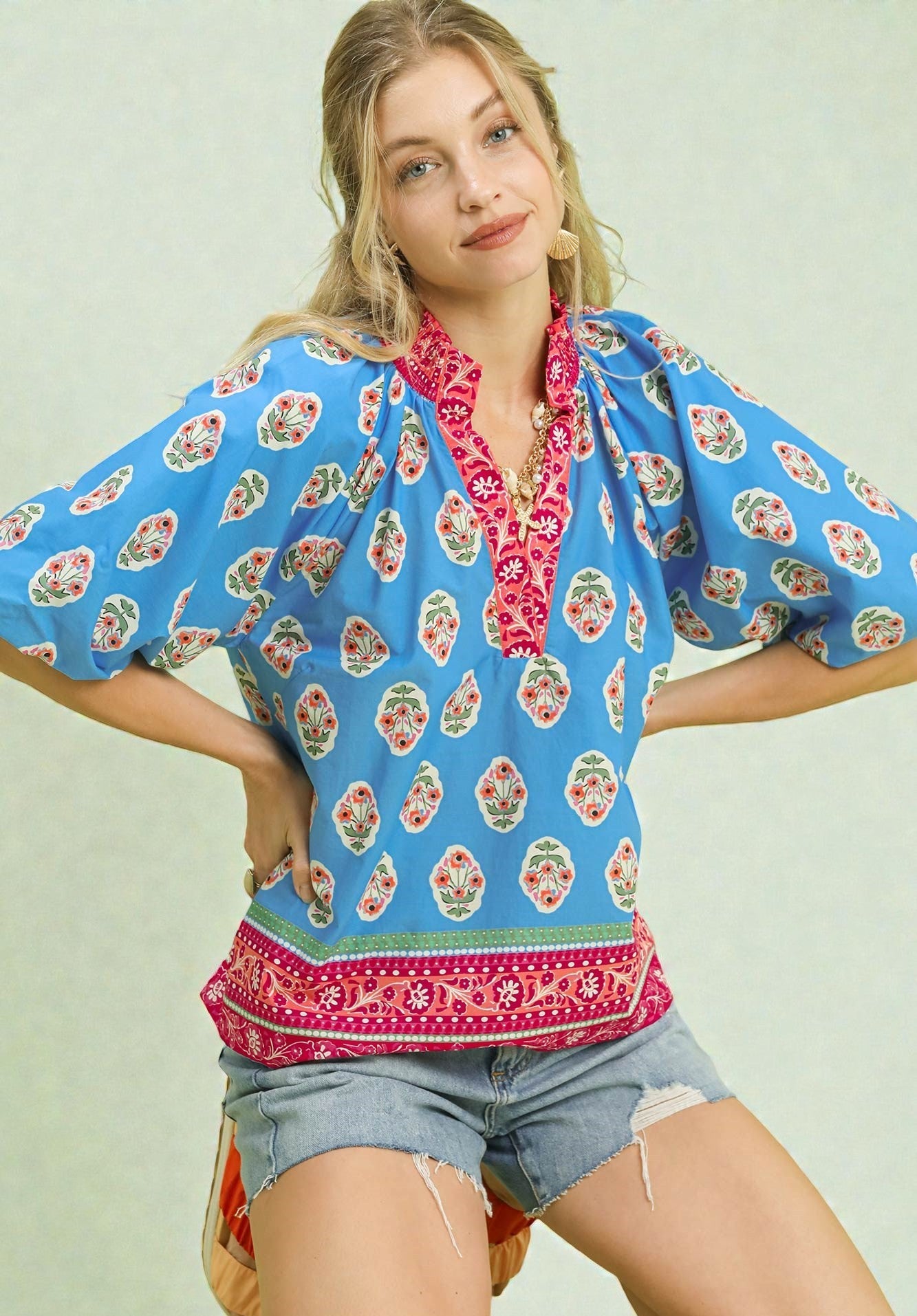 Woman wearing a colorful blouse with floral patterns on a light background
