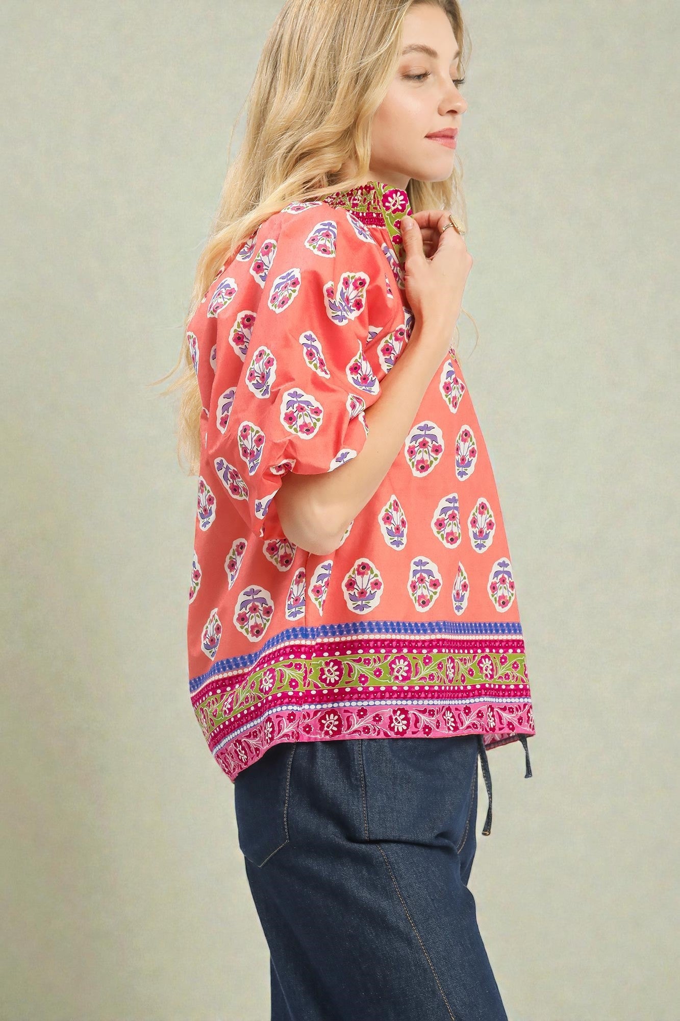 Woman wearing a colorful patterned top with a plain background