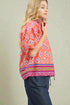 Woman wearing a colorful patterned top with a plain background