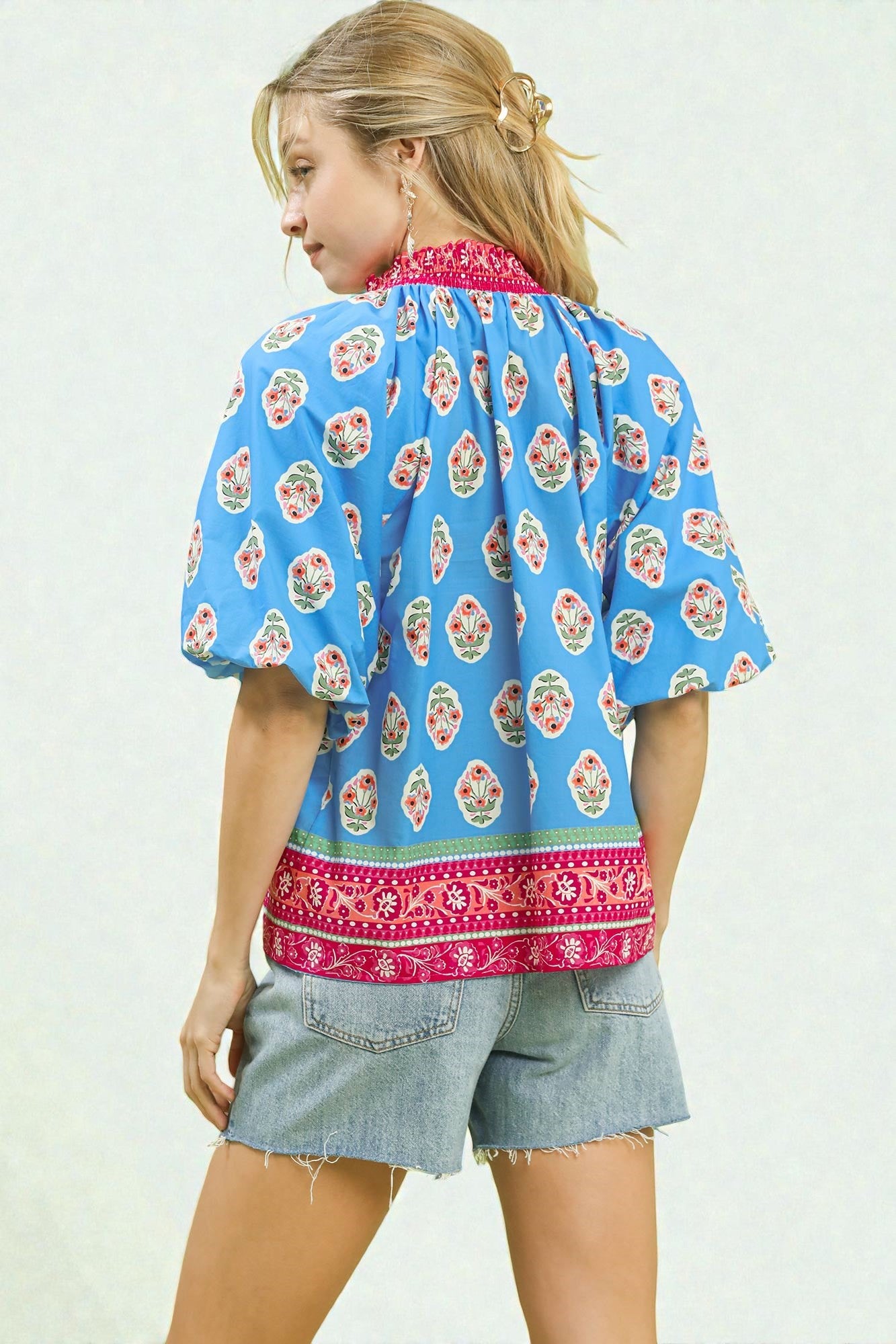 Woman wearing a blue floral blouse with red accents on a white background