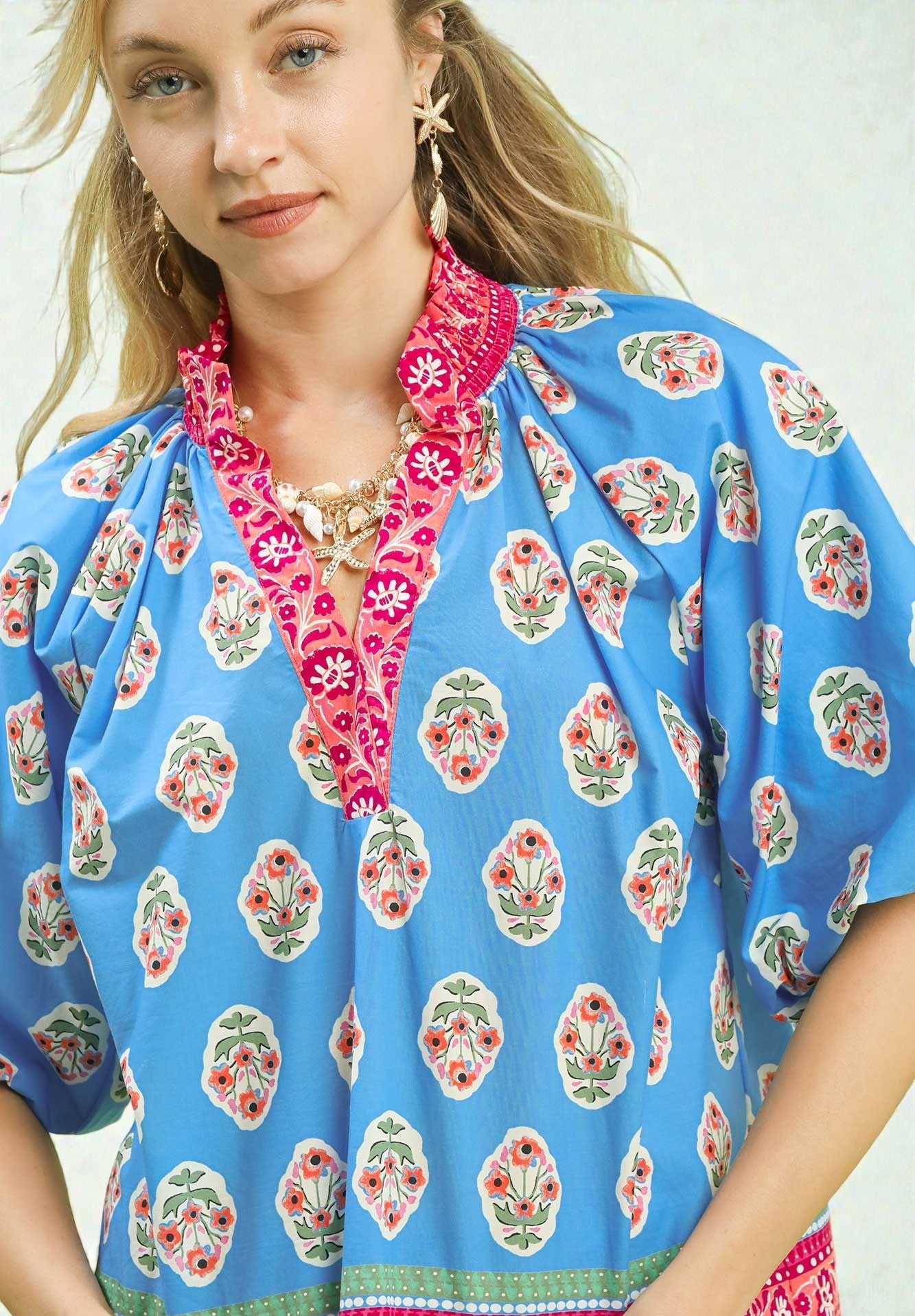 Woman wearing a blue floral blouse with pink accents on a white background