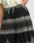Black wide-leg pleated skirt with white embroidered leaf and vine patterns, shown on a model wearing a cream top.