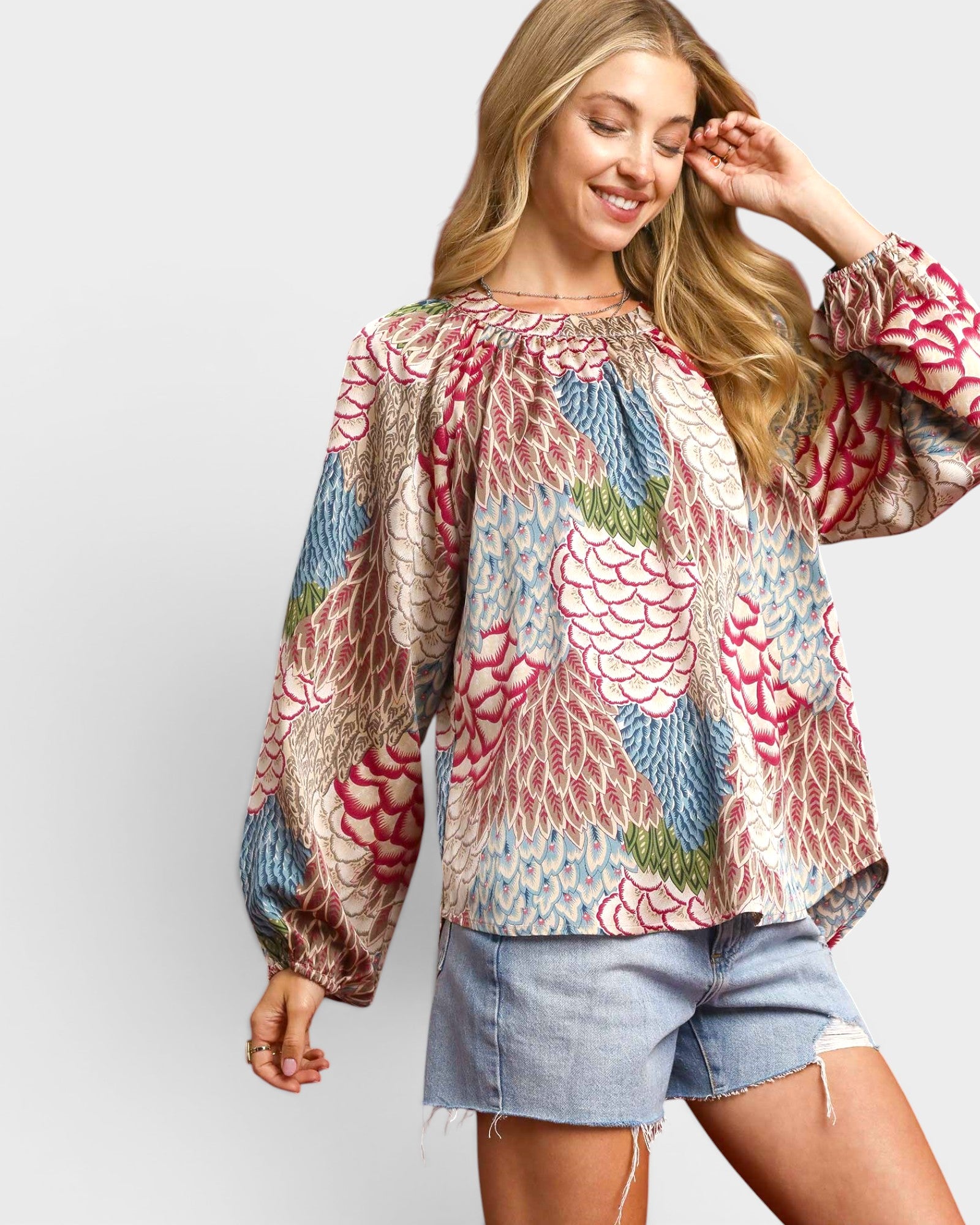 Woman wearing a colorful floral blouse and denim shorts on a white background