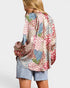 Woman wearing a colorful patterned top and denim shorts on a white background