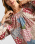 Woman wearing a colorful floral blouse with a neutral background