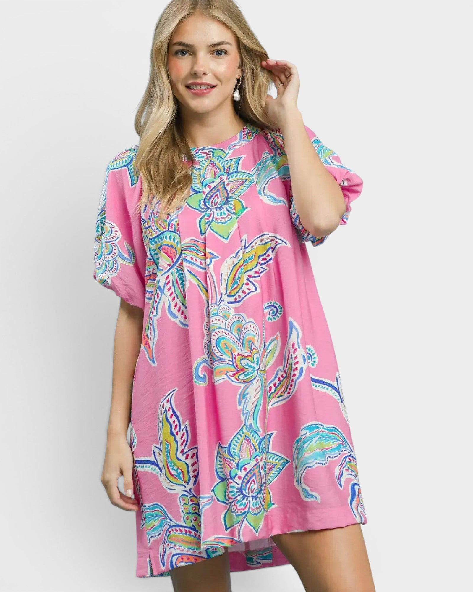 Woman wearing a pink dress with colorful floral pattern on a white background