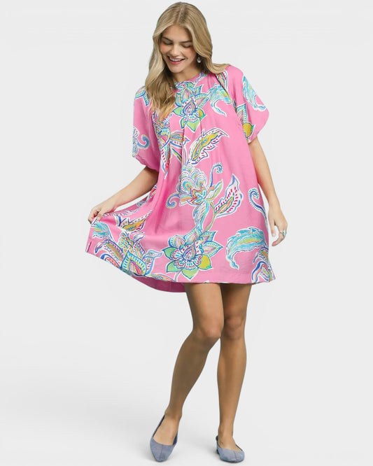 Woman wearing a pink dress with colorful floral pattern on a white background