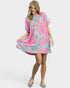Woman wearing a pink dress with colorful floral pattern on a white background