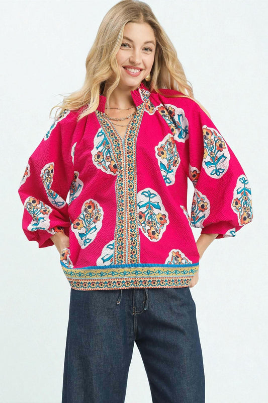 Woman wearing a bright pink blouse with colorful patterns on a white background