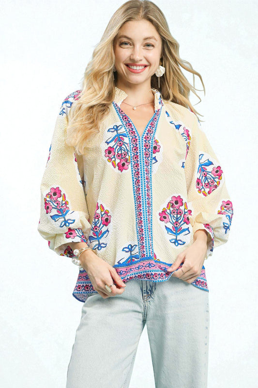 Woman wearing a beige blouse with colorful floral embroidery on a white background