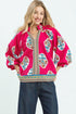 Woman wearing a bright pink blouse with colorful patterns on a white background