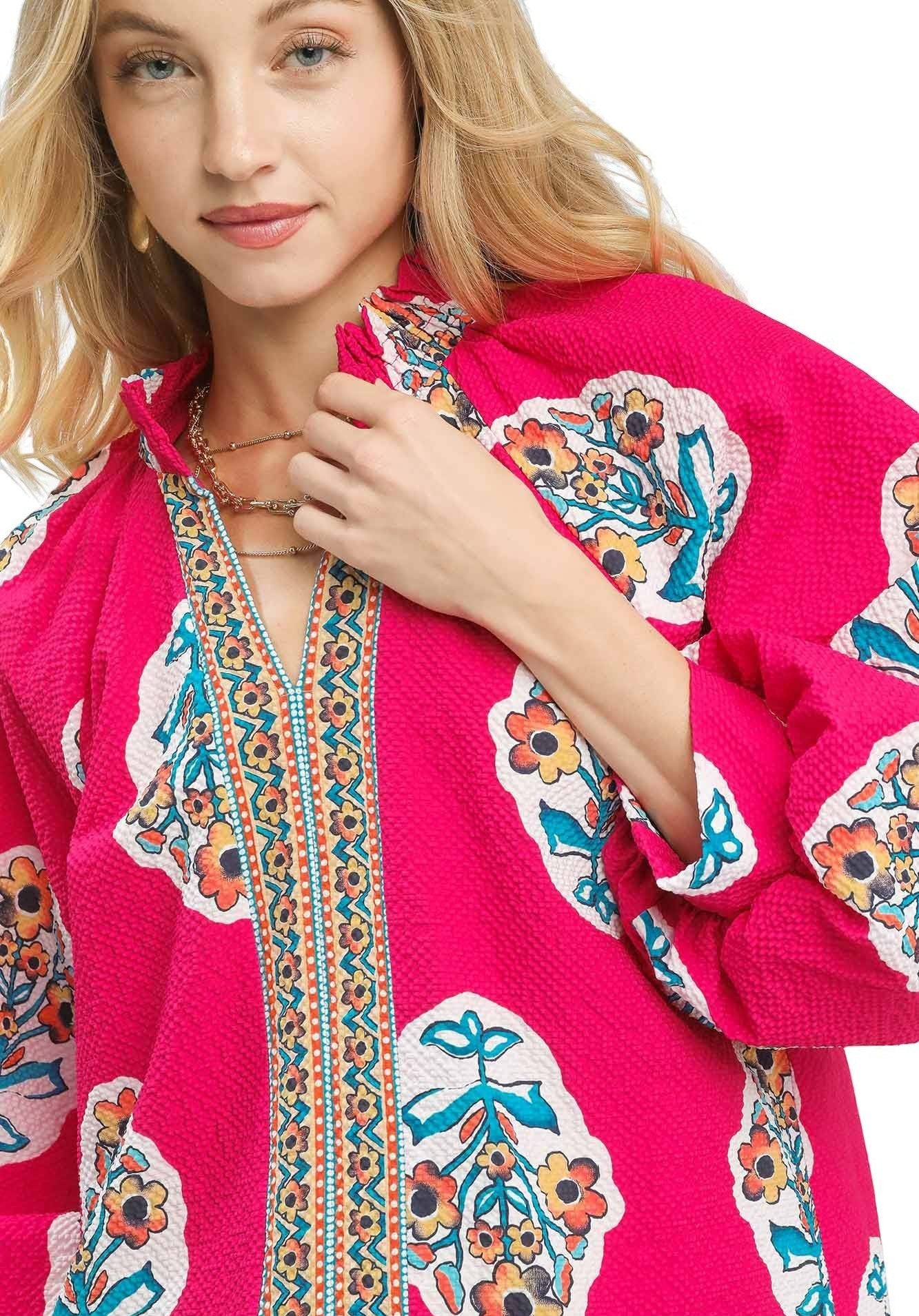 Woman wearing a bright pink jacket with colorful floral patterns on a white background